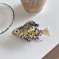 Detail view of acetate fish-shaped hair claw clip with yellow bone pattern on white surface - Spotted Fish Shape