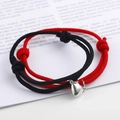 Detail of magnetic heart charms on red and black braided couple bracelets on a magazine - Black & Red (BM-0009)