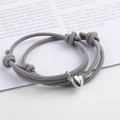Close-up of gray couple braided bracelets with magnetic heart charm and adjustable knot - Gray (BM-0009)
