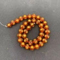 Detailed macro view of deep amber beads with gold engraved Buddhist mantra symbols - 10mm / Red Agate Wealth God Style (MS-0029-红玛瑙财神)