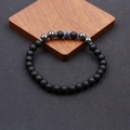 Classic beaded anklet featuring matte black stones and blue marble accent on wood block - Weathered Stone