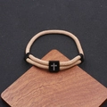 Pulsera trenzada caqui clásica con amuleto de cruz negra sobre un soporte de madera - Caqui
