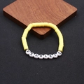 Detailansicht des gelben Heishi-Perlenarmbands mit weißen FEARLESS-Buchstaben und Goldperlen - Gelb FEARLESS-Stil