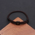 Detail of cross engraved black stainless steel block on dark brown woven cord bracelet - Coffee