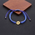 Detailed shot of dark blue woven friendship bracelet with yellow sunflower pendant detail - Blue