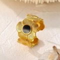 Détail macro d'une bague fleur en or mat réglable avec un insert central noir élégant - Style Incrusté Noir (R-0054)