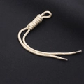 Dettaglio di un ciondolo in paracord intrecciato beige con nodo a spirale e punte trasparenti - Albicocca + Pois Bianchi (KC-0097)