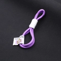 Detail eines violetten geflochtenen Seilanhängers mit gewebtem Logo auf schwarzem Grund - Lila Etikett