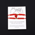 Detail of red handmade braided couple bracelets with magnetic heart charm on display card - Red Rope Red Magnetic Heart