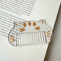Macro di un pettine per capelli in acrilico trasparente a forma di gatto su un libro - Bianco Trasparente