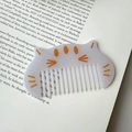 Dettaglio di un pettine per capelli a gatto viola su un libro d'arte aperto - Bianco