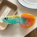 Close-up detail of acetic acid fish-shaped hair claw with vibrant orange and green gradients - Orange Peacock Fish 11.5cm