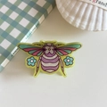 Detail der gelben Haarklammer aus Acryl im Insekten-Design mit bunten Mustern - Grüner Schmetterling