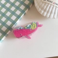 Detail einer pinkfarbenen Walknochen-Haarklammer aus Acetat auf grünem Karo-Hintergrund - Wal