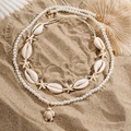 Detalle de collar de cuentas con tortuga marina, conchas y estrella de mar sobre arena - Dorado (04609)