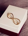 Dettaglio di un fermaglio per capelli dorato a forma di infinito su confezione - Infinito Oro (H24)