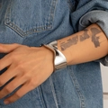 Dettaglio del bracciale in metallo lucido con design irregolare su sfondo in denim - Argento(02392)