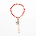 Double-layered golden bracelet featuring red faceted beads and a circular grey stone pendant - Red Beads with Round Stone Charm