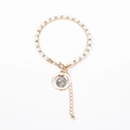 Detail view of a double-layered gold beaded bracelet with blue stone pendant and lobster clasp - Creamy White Beads with Round Stone Charm