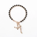 Detail of beaded bracelet with black shiny beads, gold chain, and arrow charm detail - Black Beads with Anchor Charm