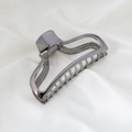 Macro detail of the dark gray metal hair claw clip with hollow geometric frame design - Gun Black