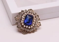 Dettaglio di spilla vintage dorata con grande cristallo blu e alone di perle - Blu