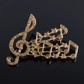 Macro d'une broche note de musique avec strass champagne sur une surface noire polie - Café