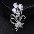 Elegante boeketbroche met druppelvormige zirkonia en strikdetail op zwarte achtergrond - Platina Magnolia