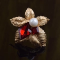 Detalle del broche de flor con hojas doradas, cristales rojos y una perla blanca - Perla Rojo Vino