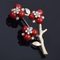 Detailed macro view of gold plum blossom brooch with red berries and inlaid rhinestones - Red