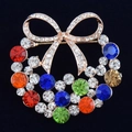 Elegante spilla a corona con fiocco e cristalli colorati su sfondo nero intenso - Fiocco Multicolore