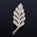 Macro detail of leaf brooch featuring gold plating and shimmering clear rhinestones - White