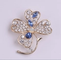 Dettaglio ravvicinato di una spilla a quadrifoglio dorata con cristalli blu e diamanti - Quadrifoglio / Stile Cristallo a Quadrifoglio