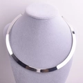 Dettaglio di un girocollo minimalista in metallo argento su un supporto in velluto grigio - Argento