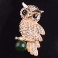 Macro-opname van een gouden uil-broche met strasstenen en groene edelsteen op fluweel - Gouden Uil Stijl (Groot)