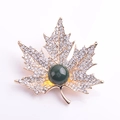 Dettaglio della spilla a foglia d'acero dorata con cristalli e pietra preziosa verde - Foglia di Acero Pavé Blu
