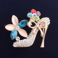 Detailopname van de broche in de vorm van een naaldhak met gekleurde kristallen - Goud