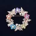 Detalle del broche de corona floral dorada con pedrería de colores sobre terciopelo negro - Guirnalda de Mariposas Colorida