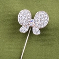 Dettaglio di spilla a farfalla con strass bianchi e gemme su tessuto verde - Stile Farfalla (Fat Butterfly)