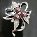 Nahaufnahme der silbernen Blumenbrosche mit lila Perlen und eingelegten Strasssteinen - Band Abstrakt Stil / Band Blatt