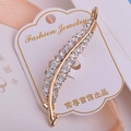 Détail d'une broche en forme de feuille dorée ornée de strass blancs scintillants - Style Feuille (xz521)