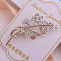 Détail macro d'une broche fleur plaquée or ornée de cristaux de strass blancs brillants - Style Bourgeon Et Feuille (xz521)