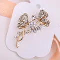 Vue détaillée de la broche papillon et fleur avec strass blancs sur monture dorée - Style Papillon Et Fleurs (xz521)