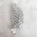 Dettaglio macro della spilla a piuma in cristallo con grande perla bianca su sfondo morbido - Bianco
