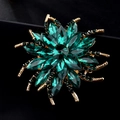 Vue macro d'une élégante broche fleur avec cristal vert émeraude et détails en alliage doré - Vert