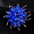 Détail d'une broche en forme de fleur avec cristaux bleus sur base en alliage doré - Bleu