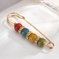 Detailed shot of creative gold brooch featuring colorful ceramic beads and rhinestones - Rainbow