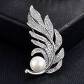 Gros plan sur une broche plume argentée avec pavé de zircons et perle blanche - Décoration Perle de Feuille