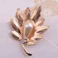 Macro shot of gold leaf brooch with leaf texture, large teardrop pearl and sparkling crystals - Gold