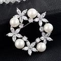 Détail de la broche ronde en perles avec fleurs en zircon sur fond en cuir noir élégant - Couronne Papillon
